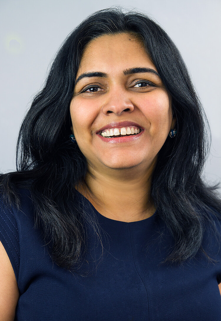 A woman with long dark hair in a navy top, smiling