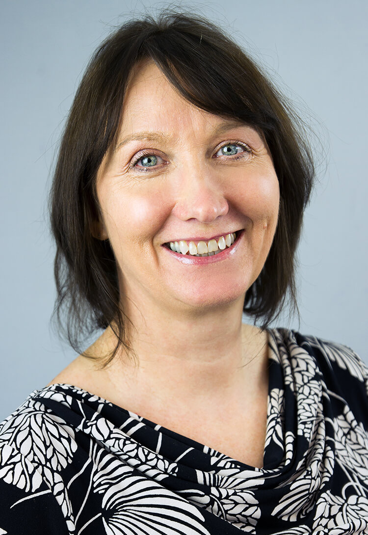 A woman with a dark bob in a patterned black and white top, smiling