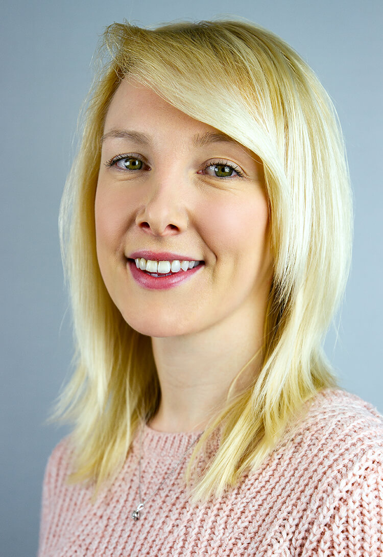 A woman with blonde hair in a pink knitted jumper, smiling