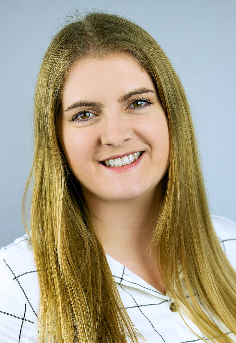 A woman with long fair hair in a white checked shirt, smiling