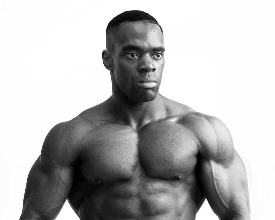 A bodybuilder photographed from the front against white, in black and white