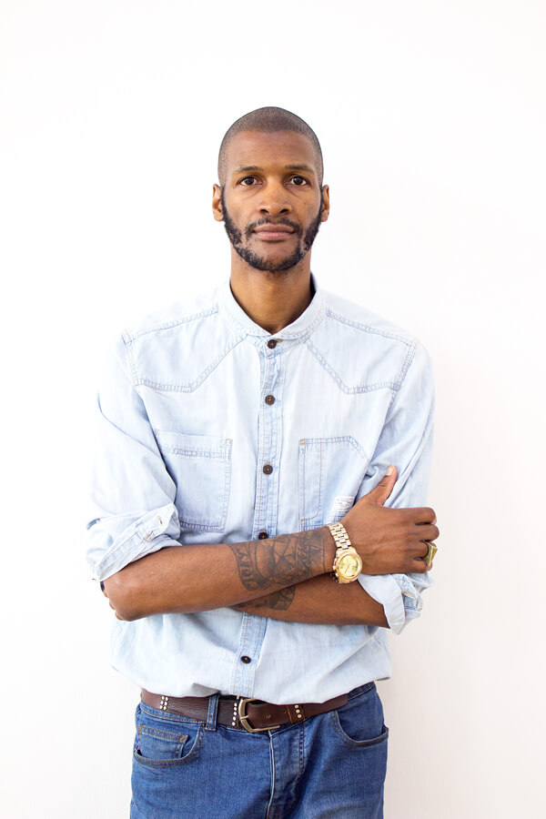 Portrait of a man in a white shirt, arms folded, against white