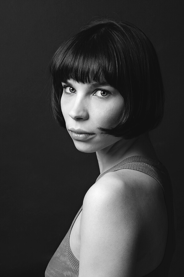 Portrait of a woman with a dark bob against a black background