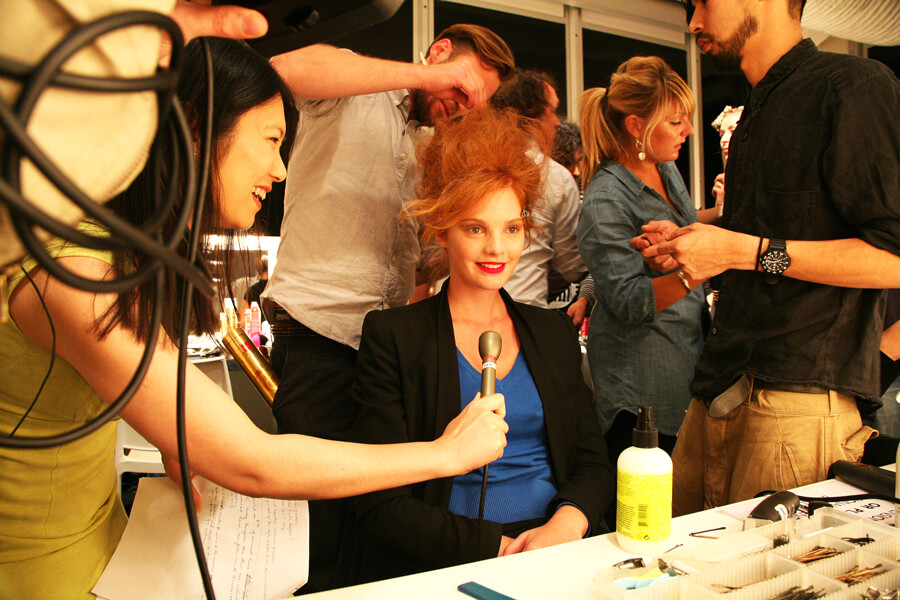 Backstage at a beauty event, hair and make-up being finished under a ring of cables