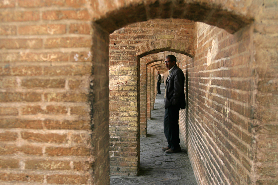 A man standing in a brick corridor of receding arches