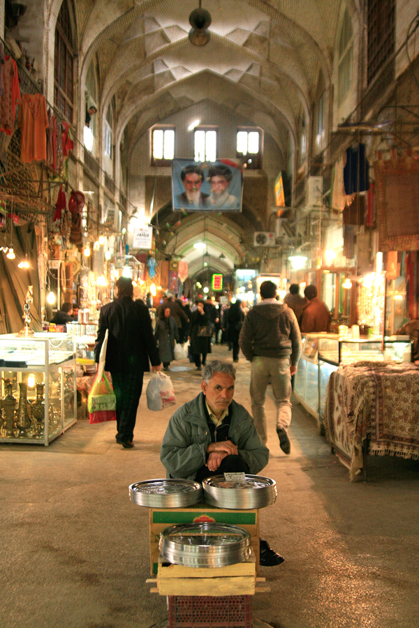 A covered bazaar in Iran, a vendor seated with his stall